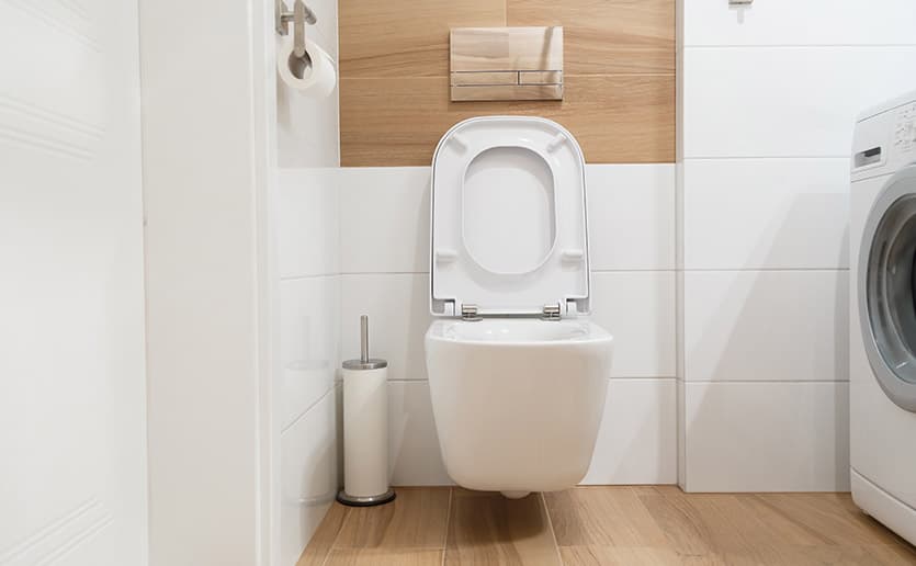 SIKO_Závěsné WC se zdvihnutým prkénkem, bílý obklad, dřevěná dlažba, podomítkový modul, stříbrné splachovací ovládací tlačítko